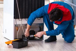 A technician is repairing a fridge